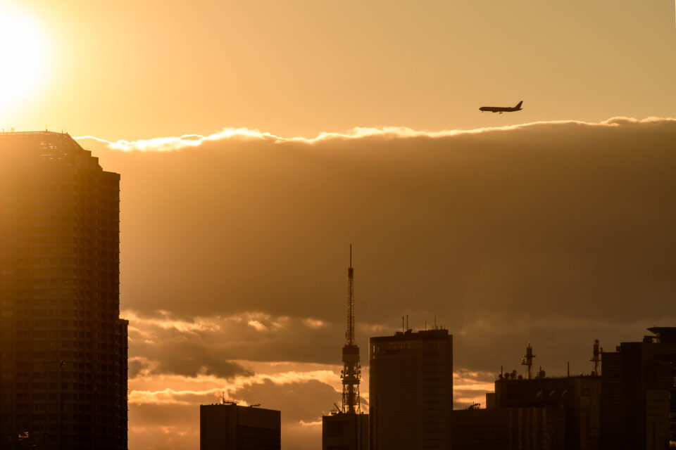 夕暮れの東京タワー上空を飛ぶ飛行機