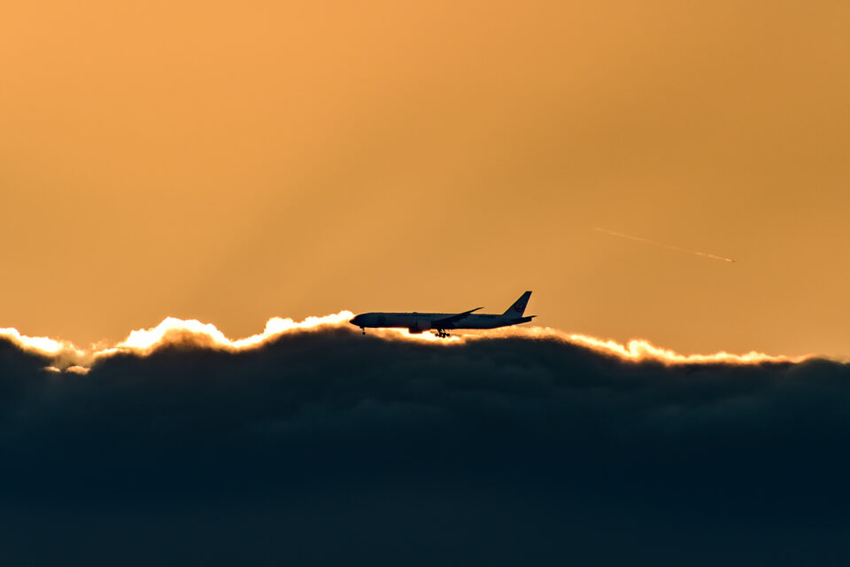 夕暮れの雲の縁を掠める飛行機