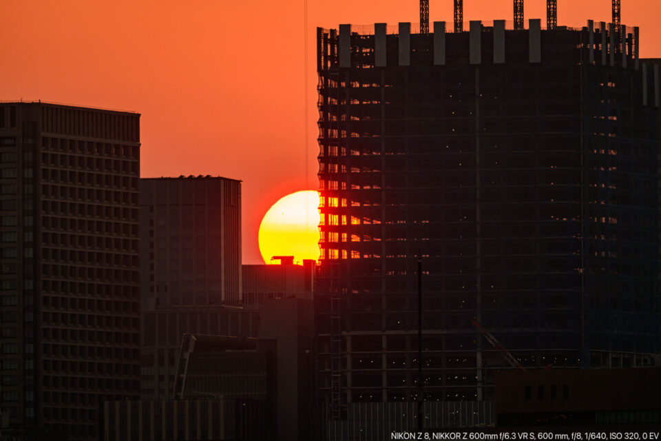 建設中のビルに沈む夕陽